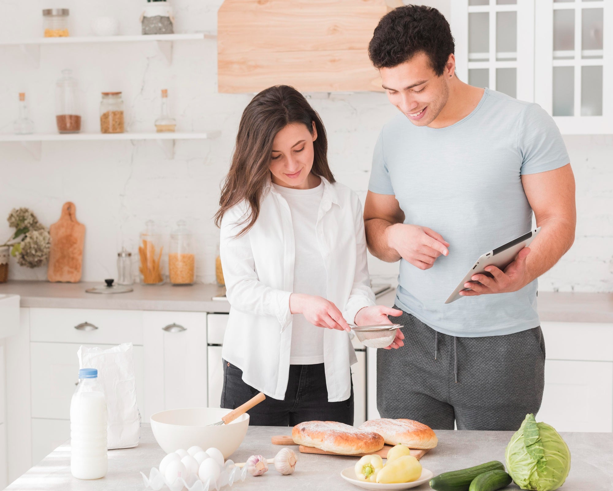couple smiling in a kitchen while cooking together