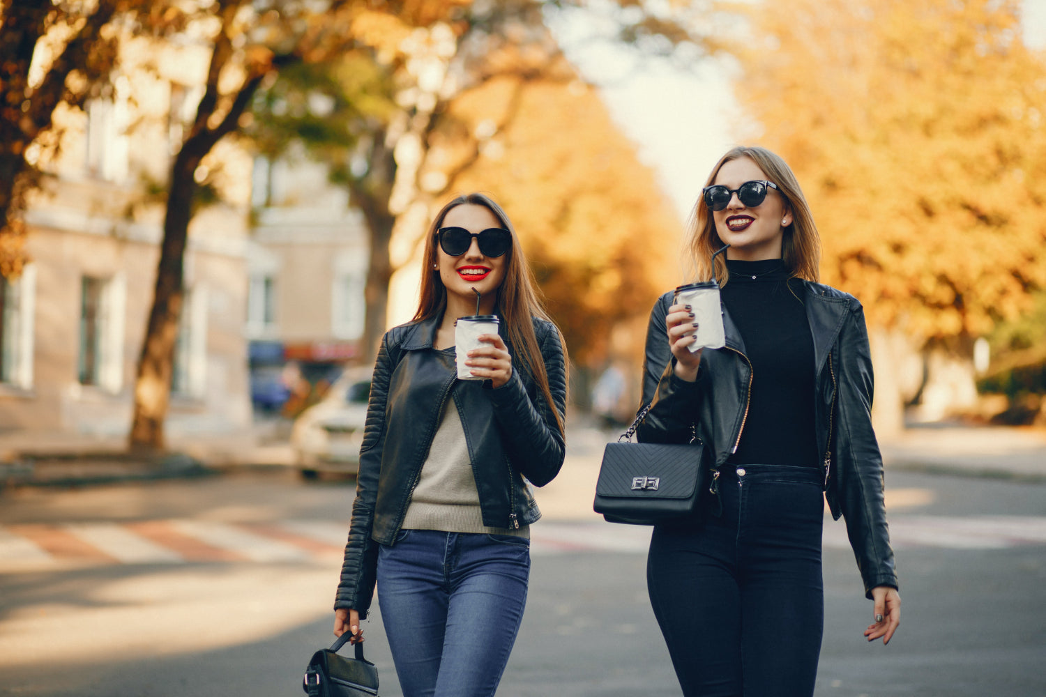 two close friends walking with coffee and smiling on a city sidewalk