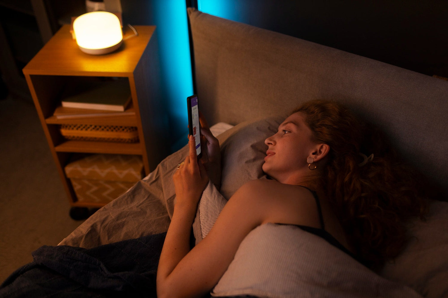 women smiling at her phone on bedroom at night, light mood, relaxed posture