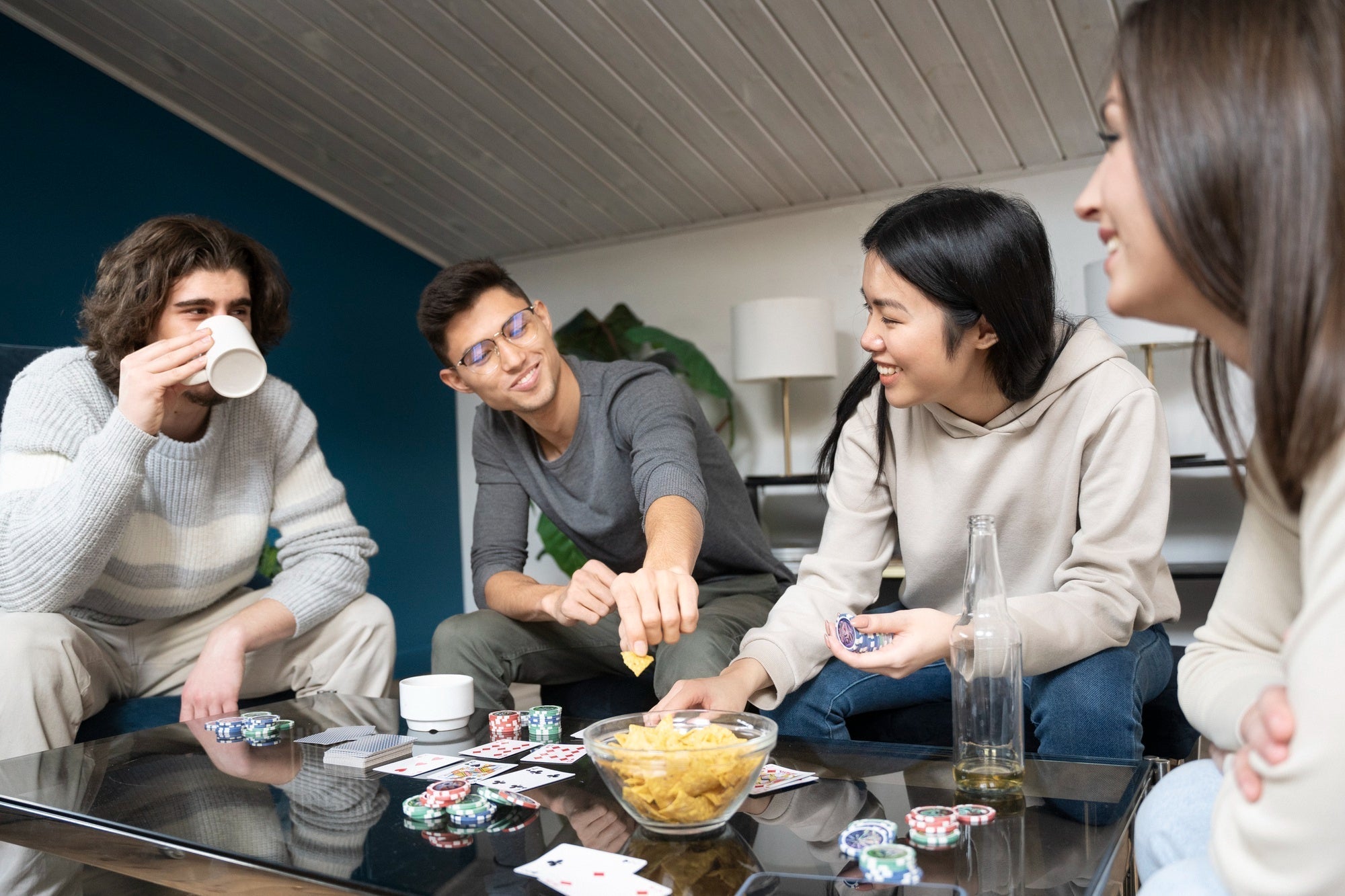 Friends around a coffee table, laughing with cards and snacks, cozy room
