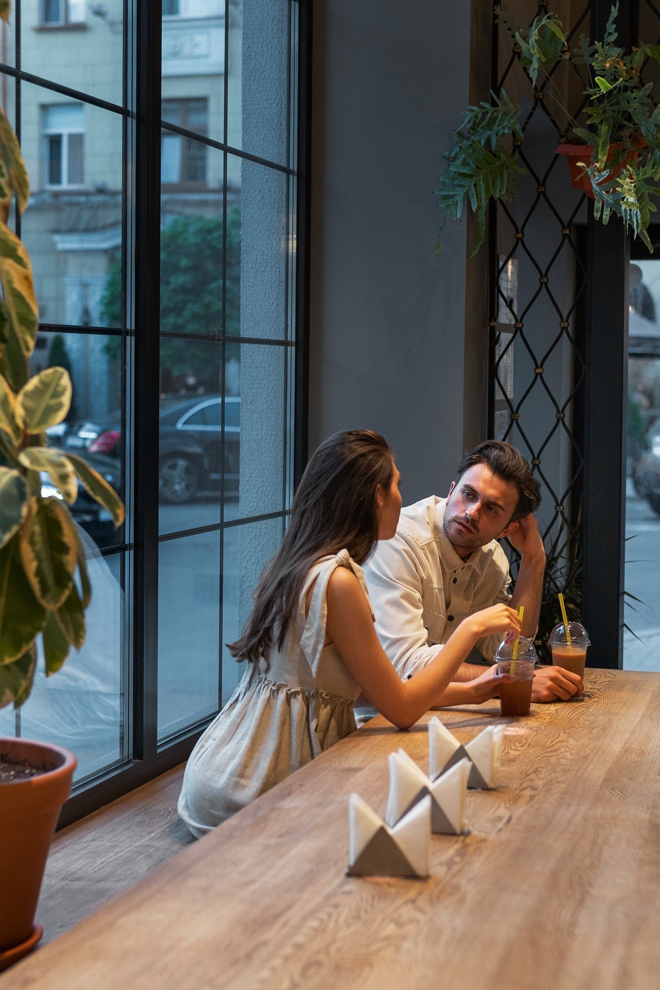 Two people laughing at a small table, soft window light, cozy mood