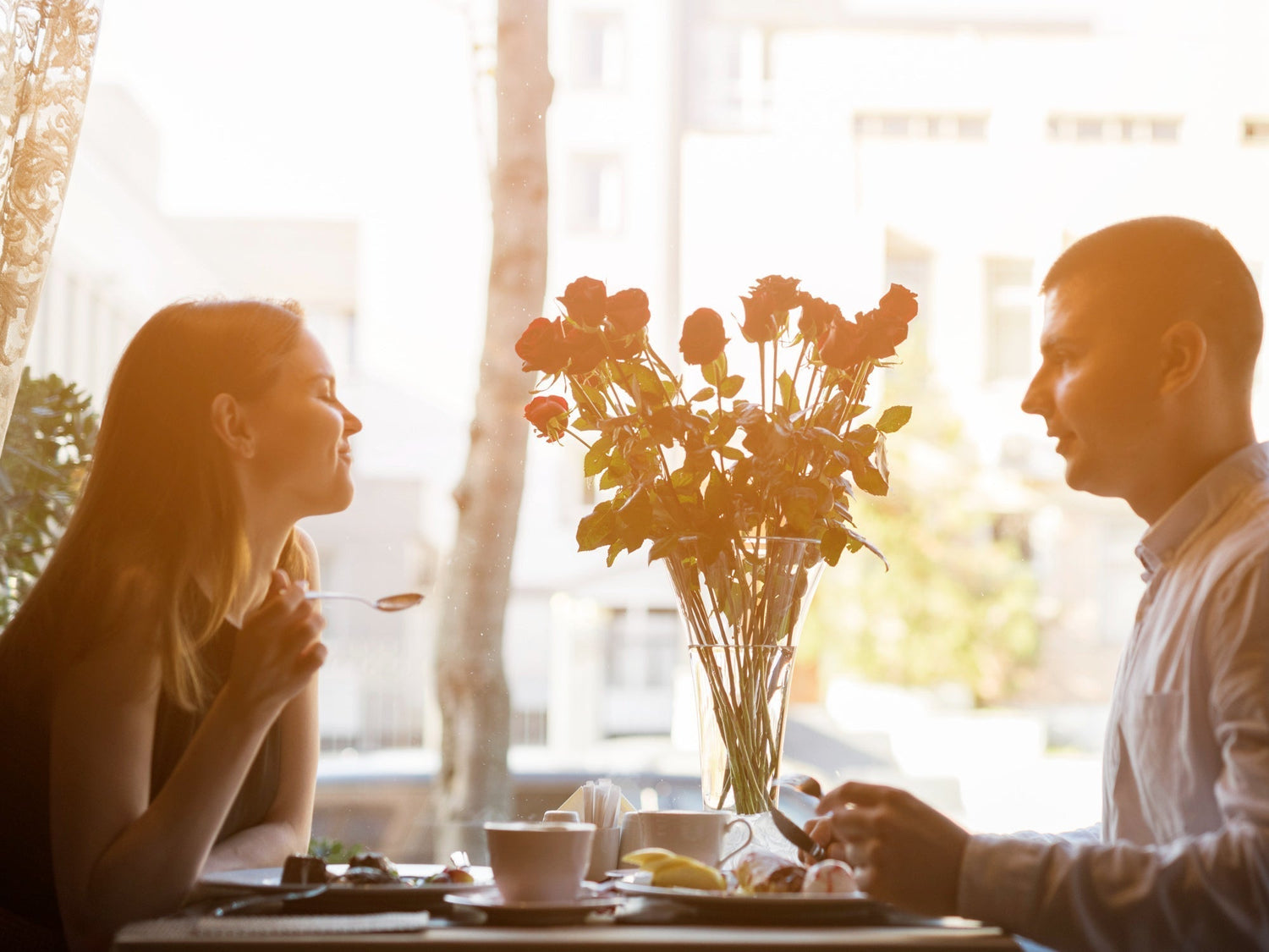 couple laughing at a cafe table with warm window light