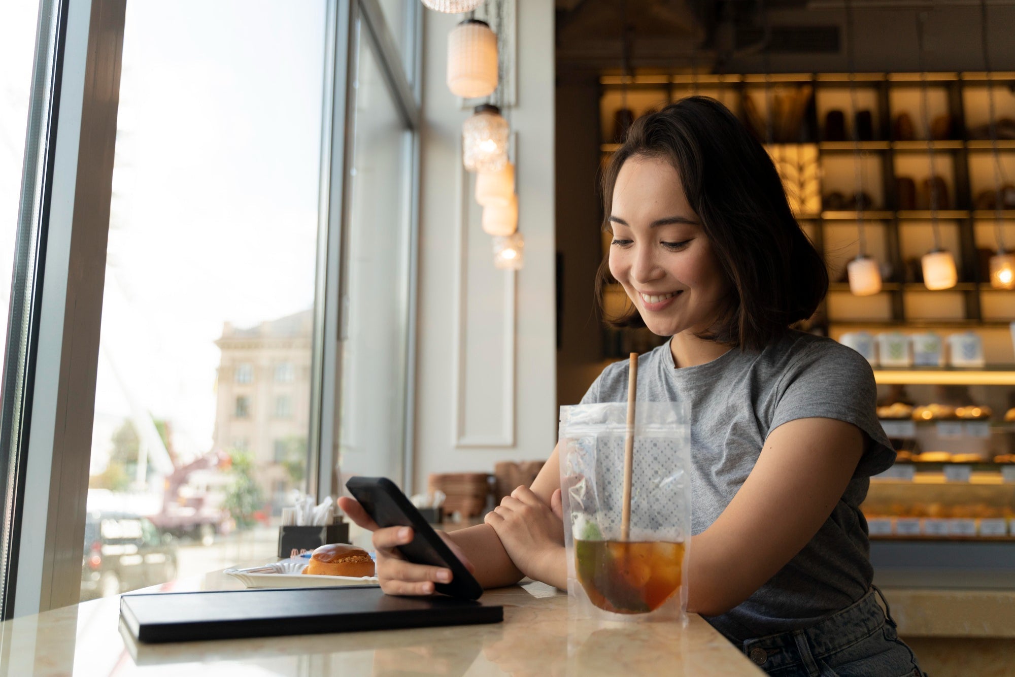 Person smiling at a phone while crafting a friendly text in a café
